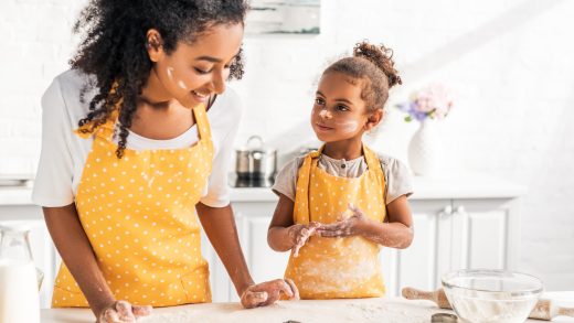 african american mother and daughter preparing cookies with molds together in kitchen