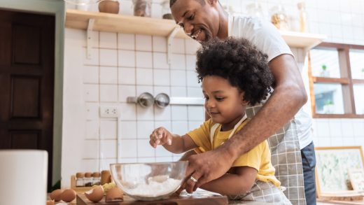 Smiling African American Father and little son while cooking in kitchen. Black family have fun while baking at home
